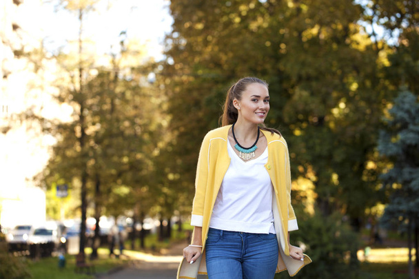 Happy young woman in yellow coat in autumn street - Photo, image