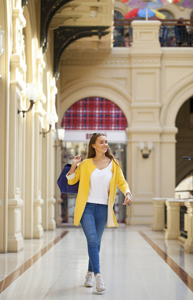 Young woman in yellow coat walking in the shop - Photo, image