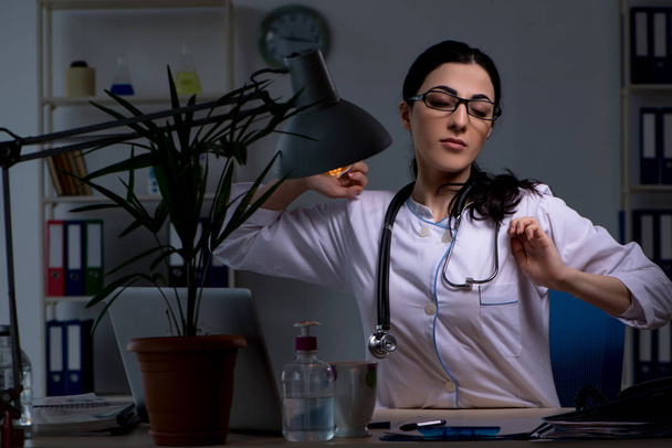Jonge vrouwelijke arts werkzaam in de nachtdienst  - Foto, afbeelding