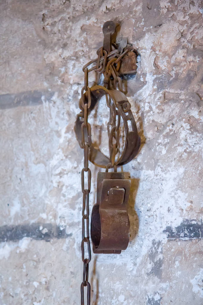 Old rusty shackles with chain on wall in prison - Photo, Image