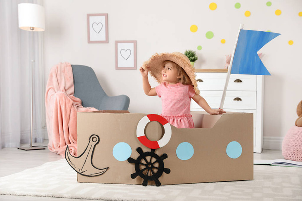 Cute little girl playing with cardboard ship at home - Photo, Image
