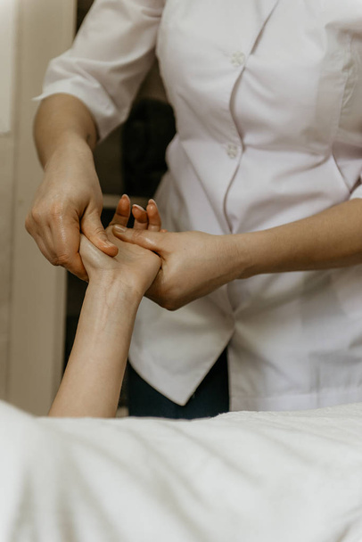 Masajista profesional hace masaje de manos a mujer joven
. - Foto, Imagen