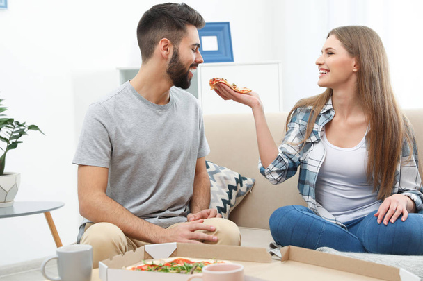 Young couple having pizza for lunch in living room. Food delivery - Photo, Image