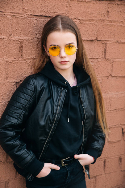 Young beautiful stylish hipster girl in sunglasses and casual clothes on brown wall - Foto, immagini