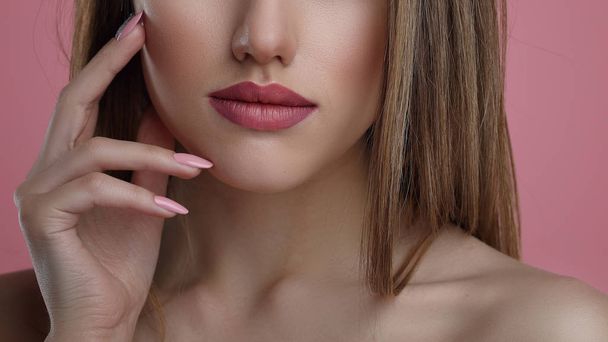 Retrato de belleza de mujer joven con flor. Chica modelo con maquillaje profesional y manicura de uñas sobre fondo rosa
. - Foto, Imagen