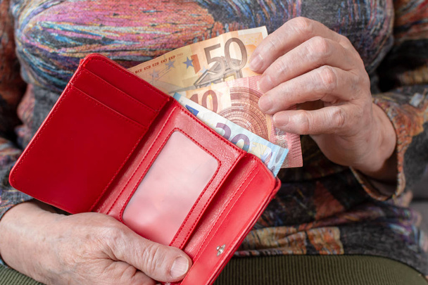 Ręce z podeszłym wieku emeryta, trzymając skórzany portfel z pieniędzmi waluty euro. Koncepcja bezpieczeństwa finansowego w starszym wieku. - Zdjęcie, obraz