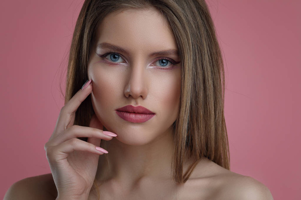 Ritratto di bellezza di giovane donna con fiore. Modello ragazza con trucco professionale e manicure Nail Art su sfondo rosa
. - Foto, immagini