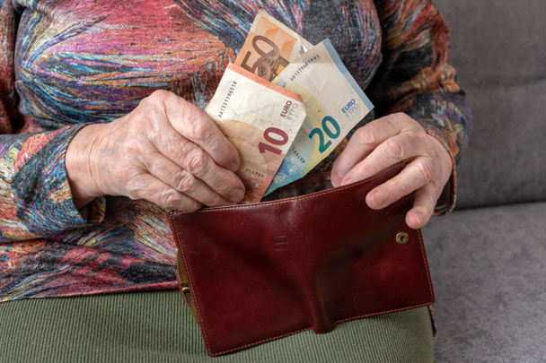 Hands of an elderly pensioner holding leather wallet with euro currency money. Concept of financial security in old age. - Φωτογραφία, εικόνα
