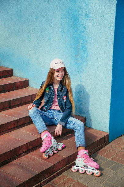 Teenager skating in city . Girl going rollerblading sitting on step - Photo, image