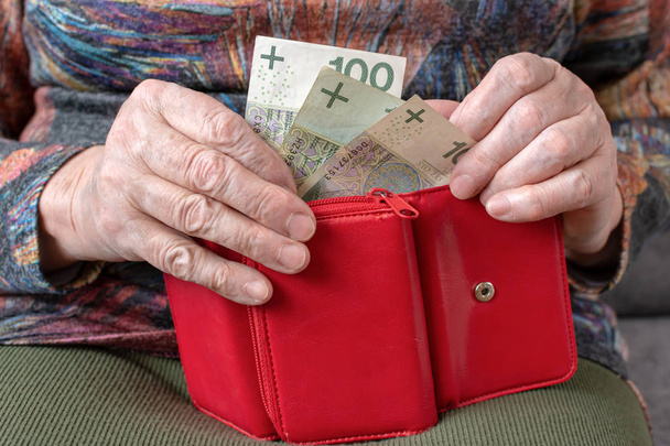 Hands of an elderly pensioner holding leather wallet with polish currency money. Concept of financial security in old age. - Φωτογραφία, εικόνα