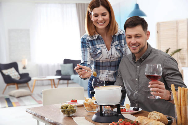 Happy couple enjoying fondue dinner at home - Фото, изображение