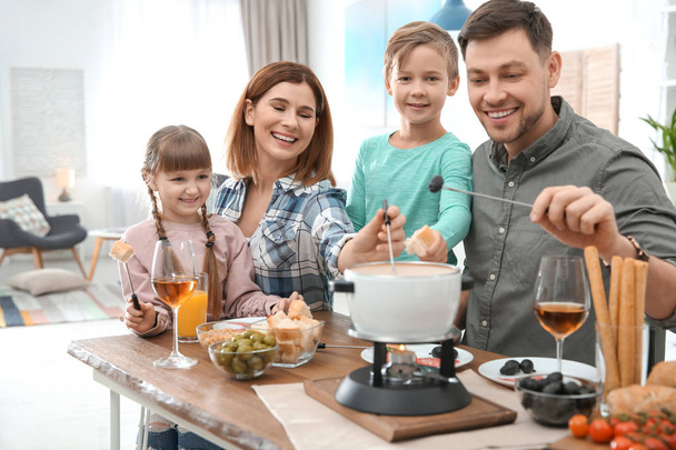 Happy family enjoying fondue dinner at home - Fotoğraf, Görsel