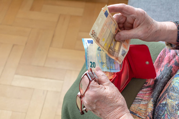 Hands of an elderly pensioner holding leather wallet with euro currency money. Concept of financial security in old age. - Foto, Bild