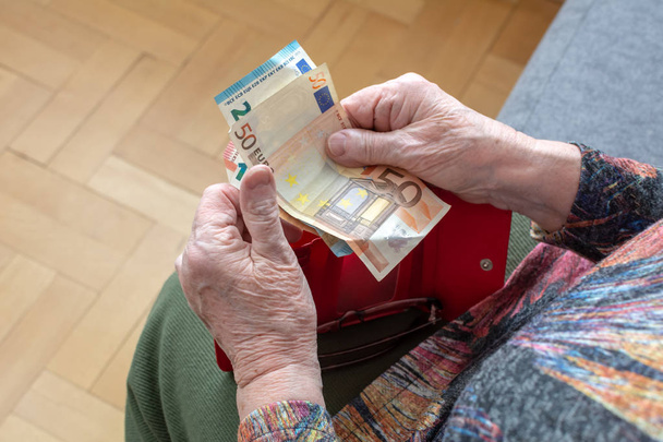Hands of an elderly pensioner holding leather wallet with euro currency money. Concept of financial security in old age. - Fotó, kép