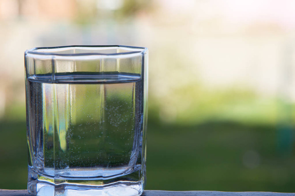Un vaso de agua limpia sobre un fondo verde
 - Foto, Imagen