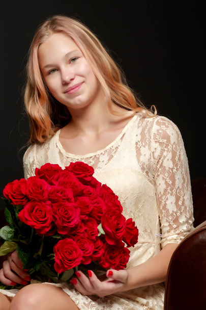 A teenage girl with a bouquet of flowers, on a black background. - Foto, imagen