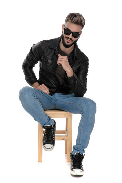 άντρας με γυαλιά ηλίου που κάθονται με τον αγκώνα με τα πόδια  - Φωτογραφία, εικόνα