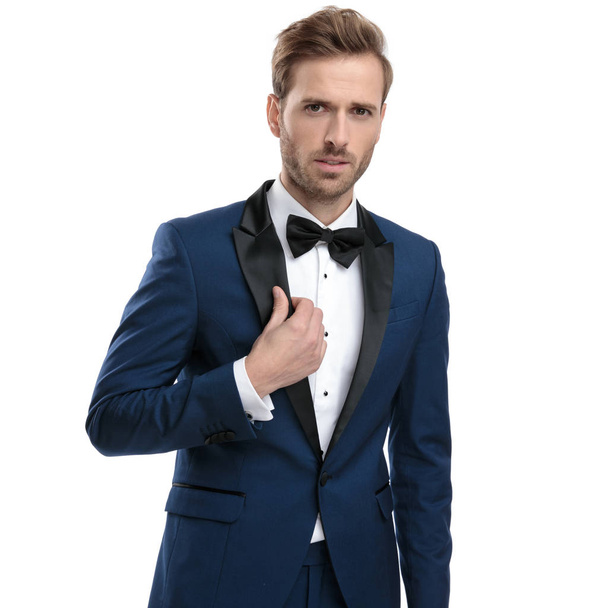 handsome guy in blue tuxedo adjusting his lounge jacket collar  - Photo, Image