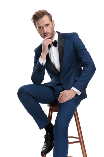 handsome man is thinking while sitting on a stool  - Foto, imagen