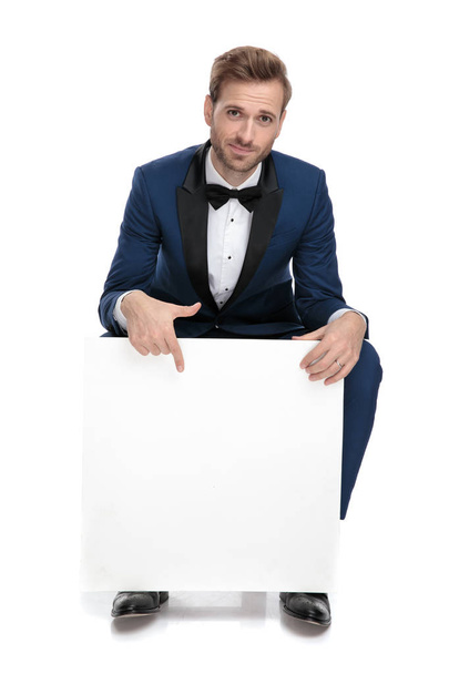 seated elegant man pointing his finger down to blank paper billb - Photo, image