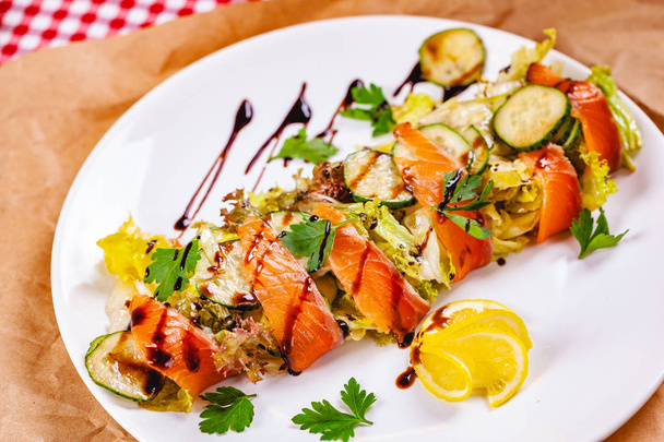 Ensalada con salmón, pepino y verduras mixtas en plato blanco. De cerca.
 - Foto, Imagen
