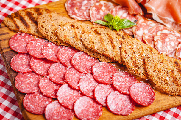 Итальянское мясо и поджаренный хлеб на деревянной доске. Закрыть - Фото, изображение