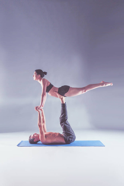 Young couple practicing acro yoga on mat in studio together. Acroyoga. Couple yoga. Partner yoga. - Foto, imagen