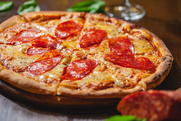 İtalyan Pepperoni pizzası mozzarella peyniri ve ahşap tahtada salam. Kapat. - Fotoğraf, Görsel