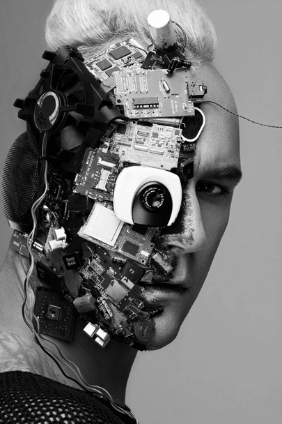 Monochrome studio photo of man cyborg, half face computer elements and with professional make-up, white Iroquois on head. Future technology concept - Photo, Image