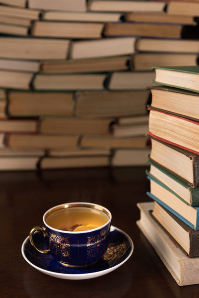 csésze tea és egy fából készült asztal sok könyvet - Fotó, kép