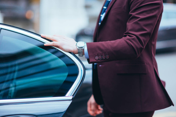 Empresário segurando a porta de sua limusina mostrando seu relógio a
 - Foto, Imagem