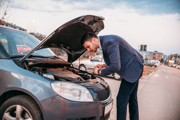 Молодий менеджер формально одягнені, перевіряючи його автомобіль нафти в sunset, wh - Фото, зображення