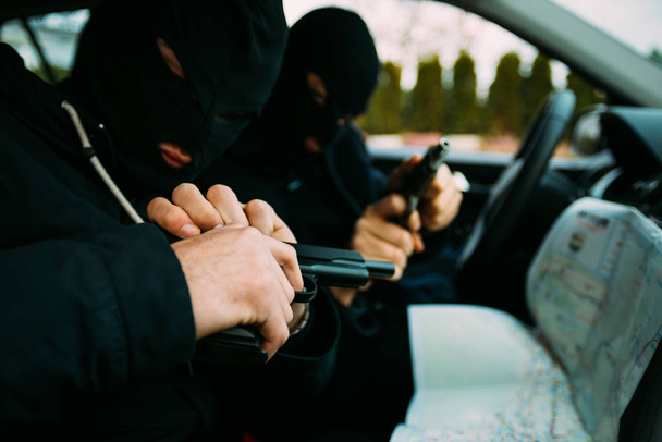 Bank robbers with their masks on pointing at the map prepared fo - Photo, Image