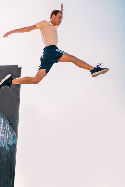 O homem esportivo faz truques de parkour enquanto salta - Foto, Imagem