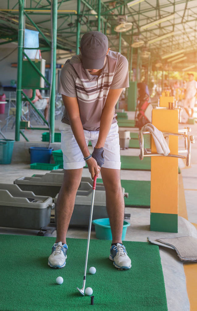 Гольф-гольф з металевим гольфом готується до їзди на м'ячі для гольфу під час практики водіння в полі для гольфу знаків
 - Фото, зображення