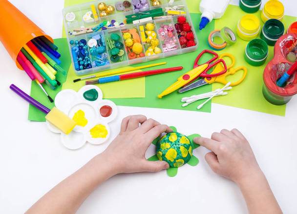 Dziecko robi zabawkę rzemieślniczą z pianki plastikowej żółwia. Materiał na kreatywność i edukację. - Zdjęcie, obraz