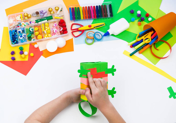Child makes a hack box chameleon. Material for creativity on a white background. - Фото, зображення