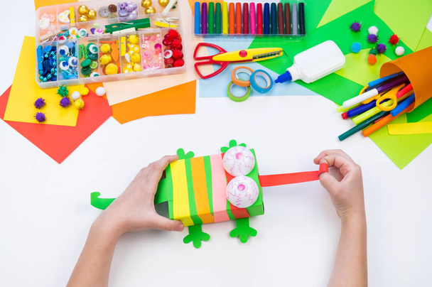 Child makes a hack box chameleon. Material for creativity on a white background. - Foto, Imagen