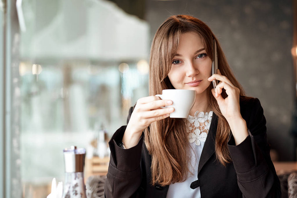 Jonge zakenvrouw praten aan de telefoon bij de coffeeshop - Foto, afbeelding