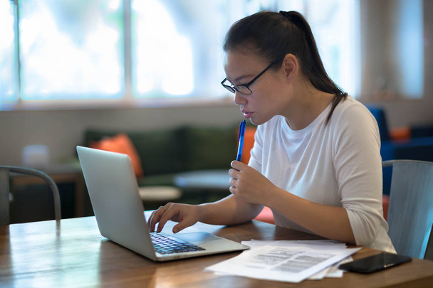 Een jonge vrouwen doen werk op haar laptopcomputer thuis. - Foto, afbeelding
