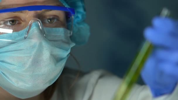 Female laboratory expert holding plant sample in test tube, pesticides influence - Materiał filmowy, wideo
