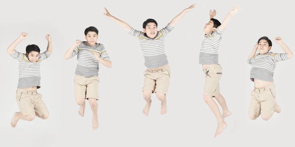 Asiatique drôle enfant garçon sautant sur fond gris
. - Photo, image