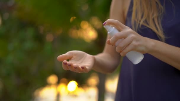 Superslowmotion shot van een mooie jonge vrouw een antimosquito repellent spray toe te passen op haar huid. Een tropische achtergrond. Mosquito verdediging concept - Video