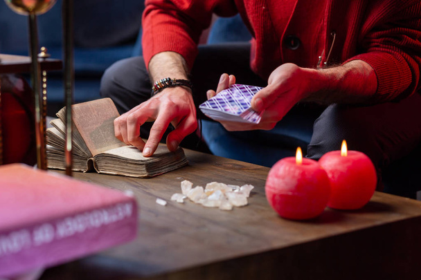 Inspired fortune-teller using old little magic book while reading cards - 写真・画像