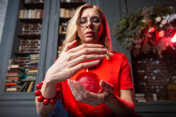 Blonde astrologist wearing massive bracelet holding burning candle - Foto, Bild