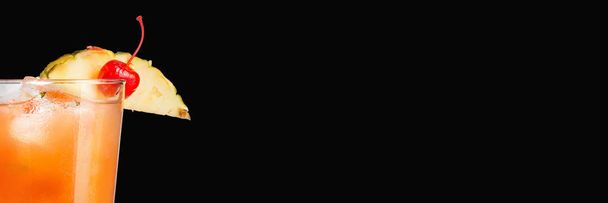 Delicioso coquetel alcoólico moderno com abacaxi e cereja marrasquino em um fundo preto. Banner de formato amplo
. - Foto, Imagem