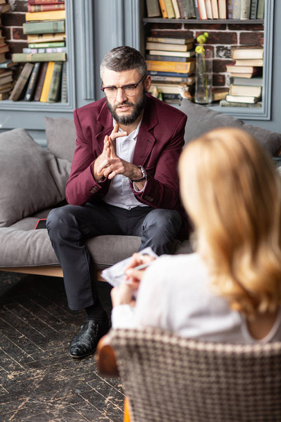 Бизнесмен в темно-красной куртке делится своими тревогами с терапевтом
 - Фото, изображение