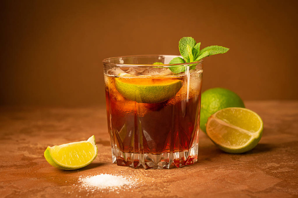 Cold iced tea in a glass on a dark brown background. Close-up. Selective focus. - Photo, image
