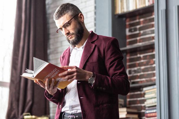 Businessman feeling interested reading book about astrology and money - Foto, Imagem