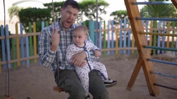 Ο μπαμπάς με ένα κουρασμένο μωρό βόλτες σε μια κούνια και χασμουριέται σε αργή κίνηση - Πλάνα, βίντεο